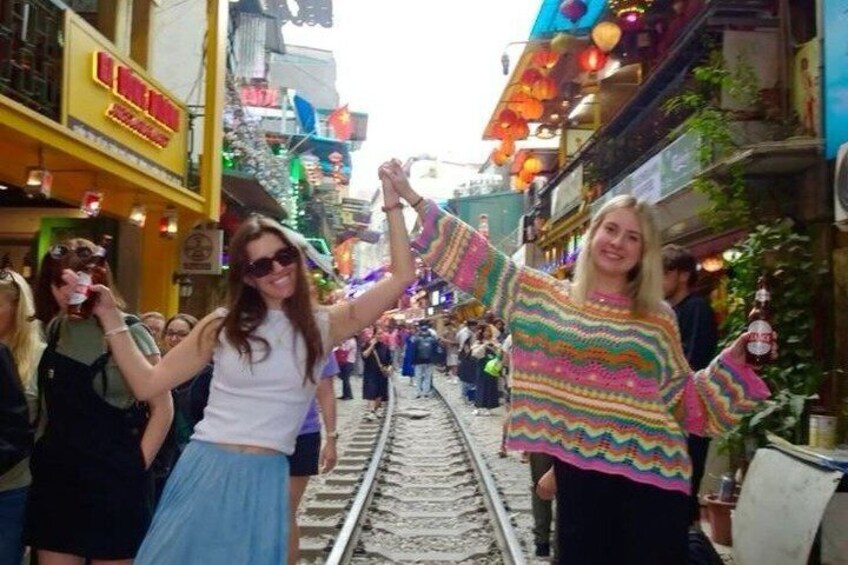 A street with a railway track, people walking, and buildings with signs. 4