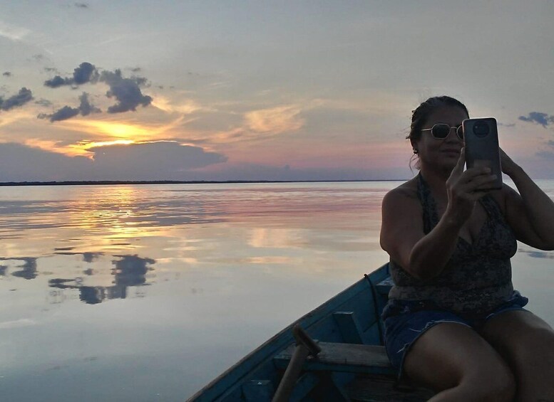 A person in a boat taking a photo with a sunset in the background. 1