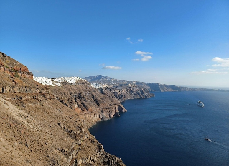 A coastal landscape with rugged cliffs, a clear blue sea, and a distant ship. 2