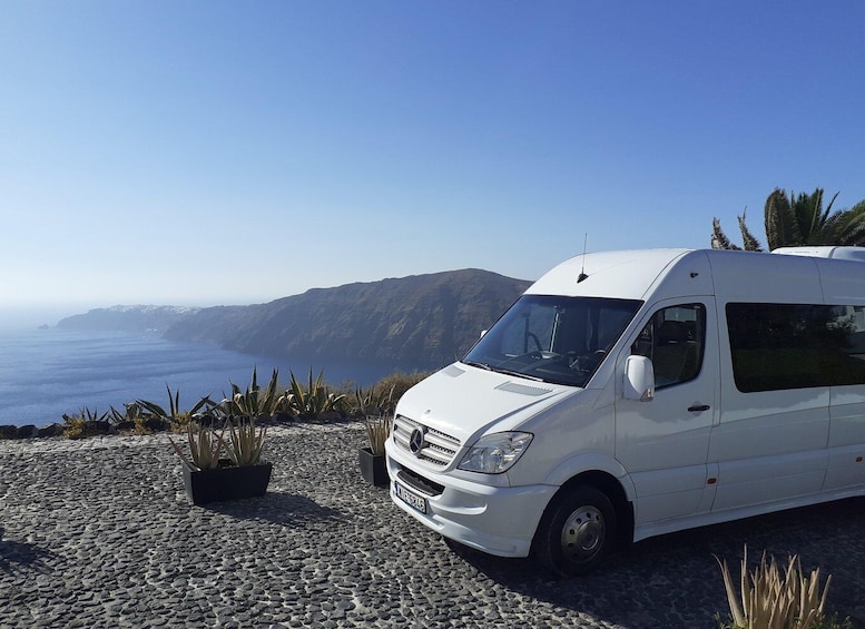 A white van parked on a rocky terrain with a coastal view. 1