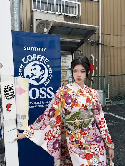 A person in a colorful kimono standing next to a Suntory Coffee sign. 3