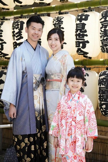 A family in traditional Japanese attire standing in front of a backdrop with Japanese characters. 4