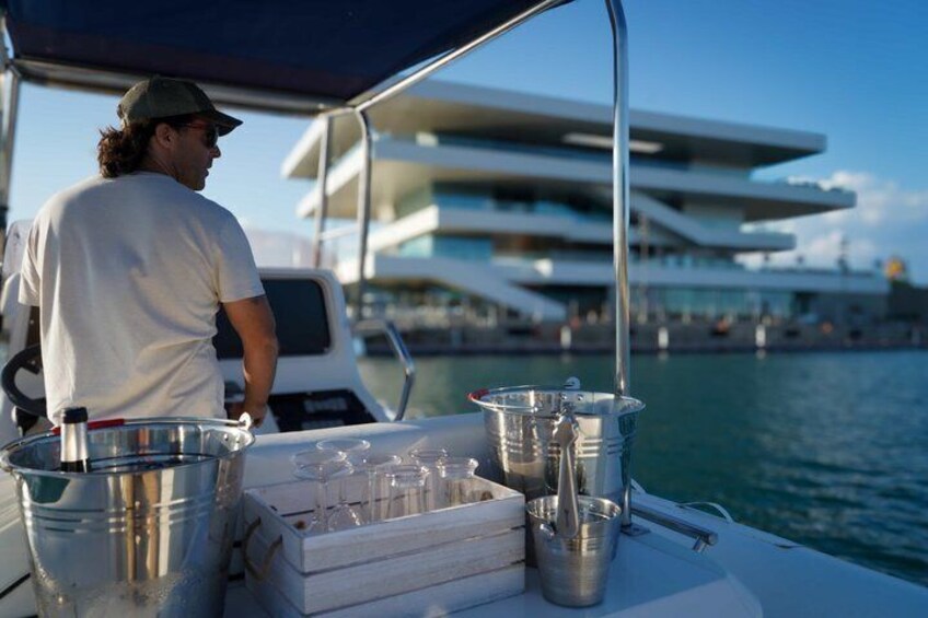 A person on a boat with a drink tray and buckets, a modern building in the background, and water. 5