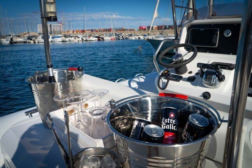 A boat's deck with a bucket of beer, a steering wheel, and a marina in the background. 3