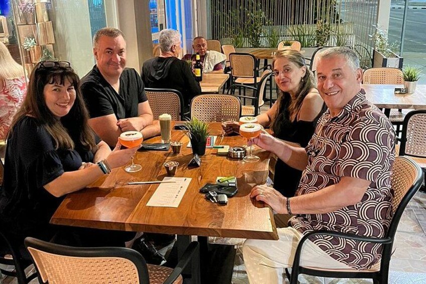 A group of people sitting at a wooden table in a restaurant with chairs and a menu. 2