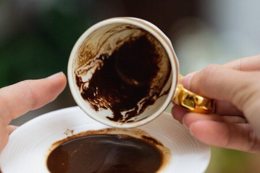 A hand holding a cup with coffee spilling onto a saucer. 1