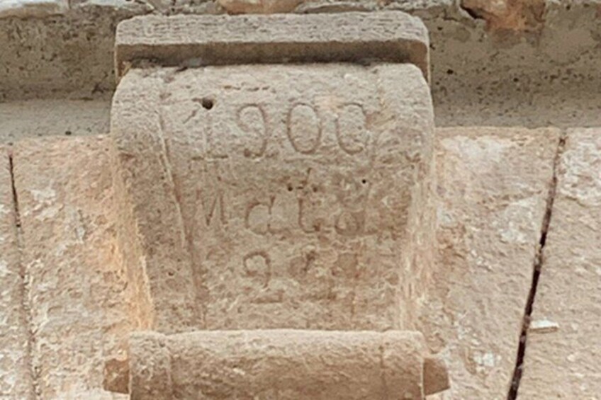A stone with carved inscriptions, including '1900' and 'M. C. 1900.' 5