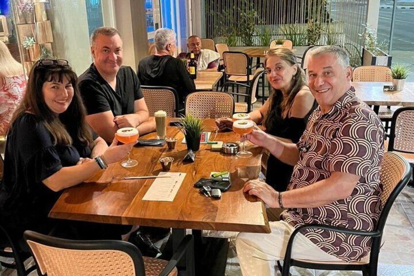 A group of people seated at a wooden table in a restaurant with chairs and a menu. 3
