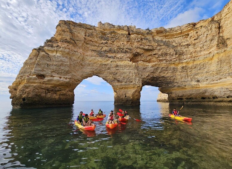 Kayakers navigating through a natural rock arch formation. 1