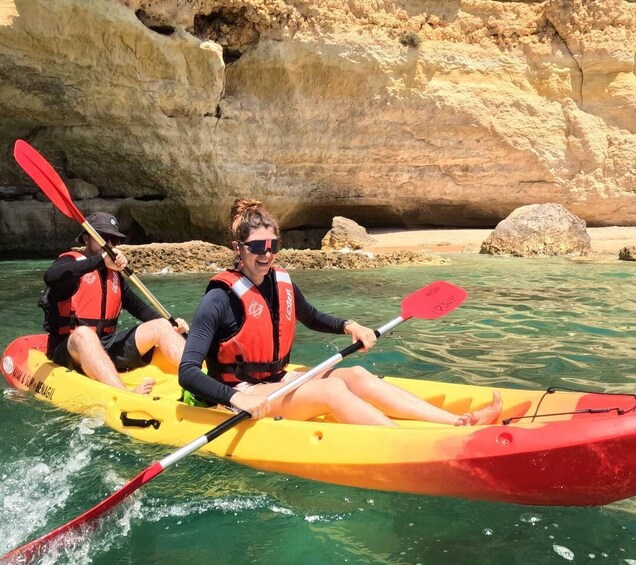 Two people kayaking on a river with clear water and rocky cliffs in the background. 2
