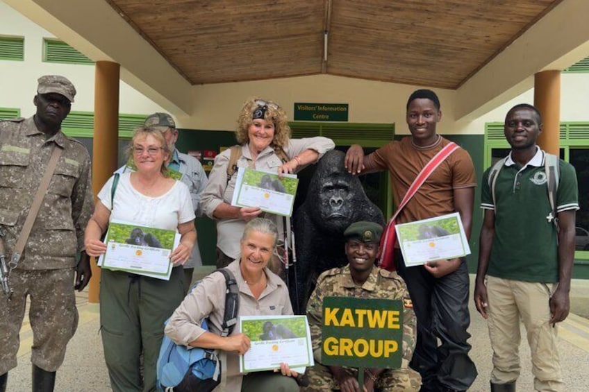A group of people posing with certificates in front of a building labeled 'VISITORY INFORMATION CENTRE.' 4