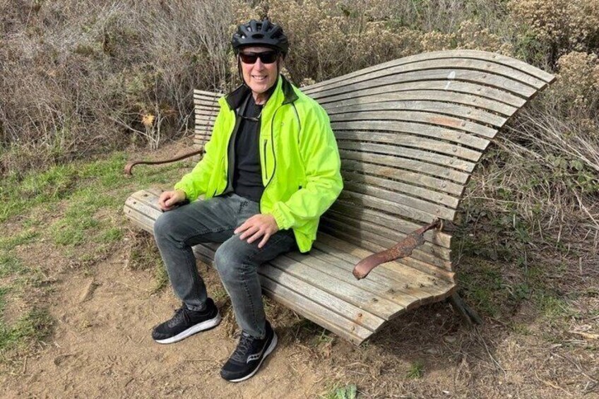 A person sitting on a wooden bench in a natural setting. 5