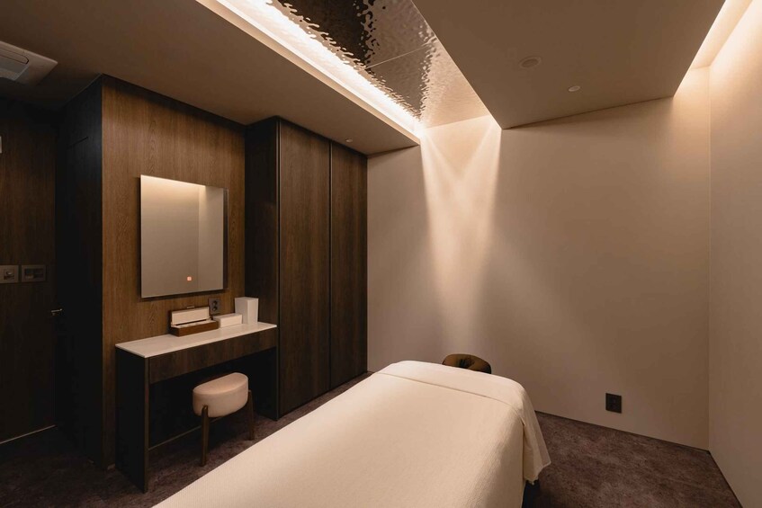 A modern bedroom with a bed, a wooden vanity, a mirror, and a unique ceiling design. 5