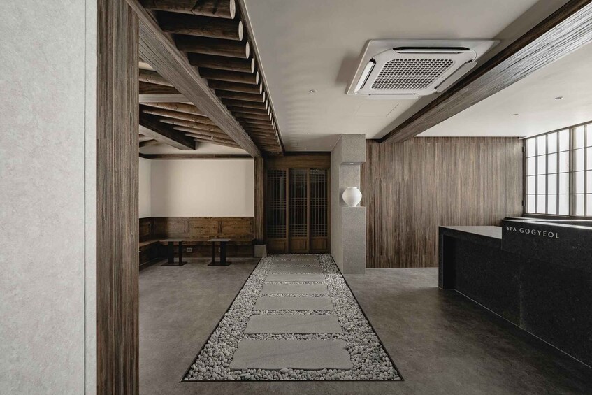 A modern interior with a stone pathway, wooden accents, and a reception desk labeled 'SPA GOGYEOL'. 4