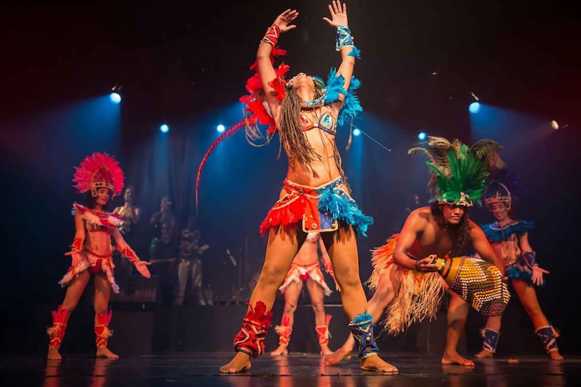 A group of performers in colorful costumes on stage. 1