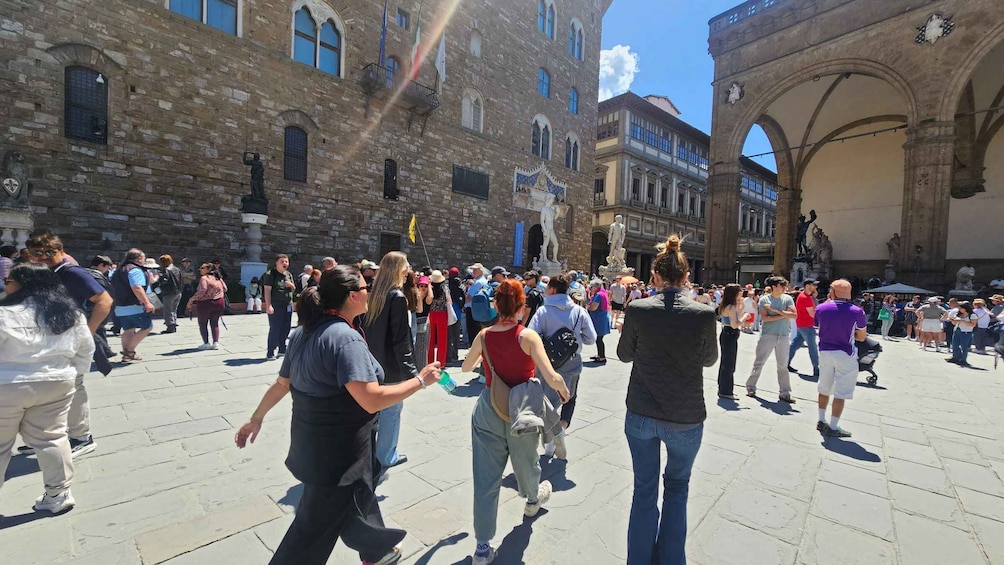 A crowded square with historic buildings and a statue. 3
