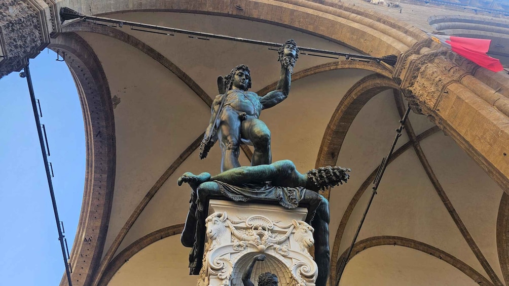 A bronze statue of a winged figure on a pedestal, set against a vaulted ceiling with intricate carvings. 2