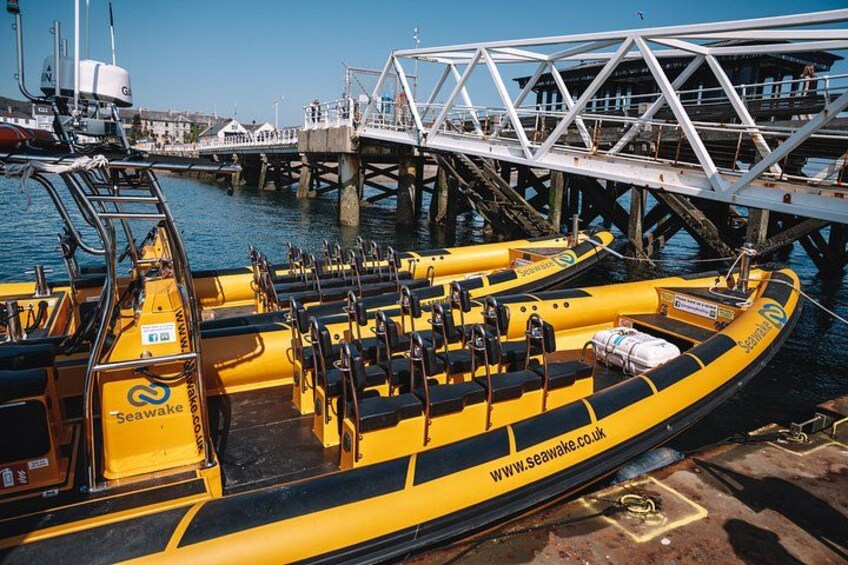 A yellow inflatable boat docked at a pier with a bridge in the background. 2