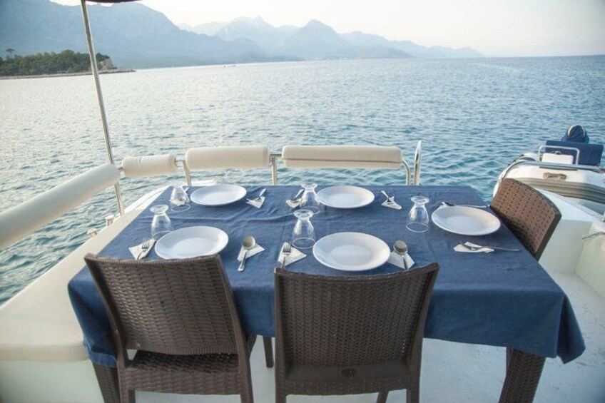 A table set for dining on a boat with a view of the sea and mountains. 5