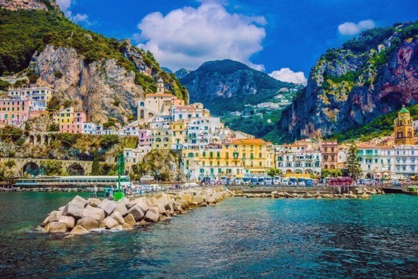 A coastal town with colorful buildings, a rocky shoreline, and a clear blue sky. 3