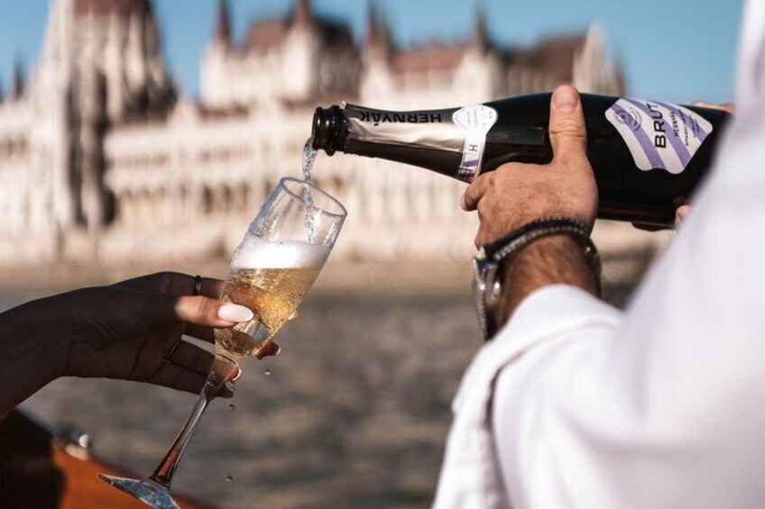 A person pouring champagne into a glass, with a historic building in the background. 3
