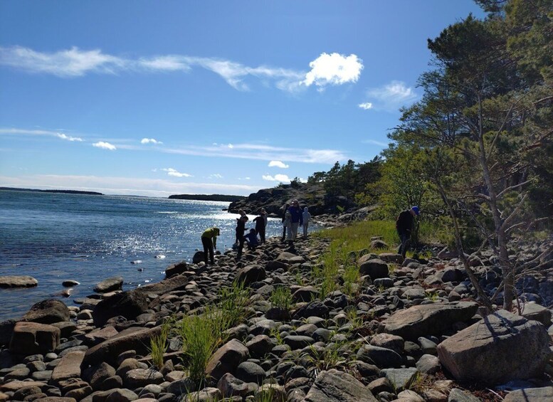 A rocky shoreline with people walking along it, a clear blue sky, and a calm sea. 4