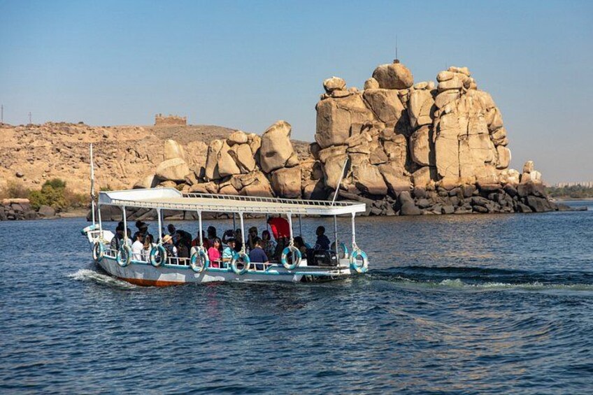 A boat with passengers on a calm river, surrounded by large rock formations and a distant castle. 2