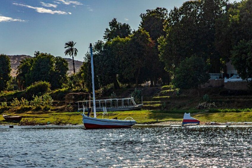 A calm lake with two boats, one larger and one smaller, surrounded by lush greenery and trees. 3
