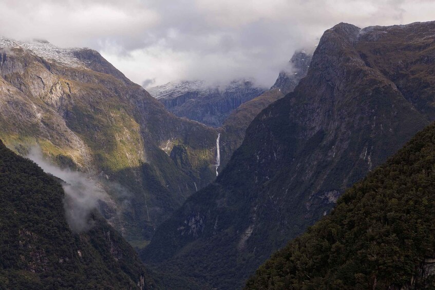 A mountainous landscape with a waterfall and dense forest. 5