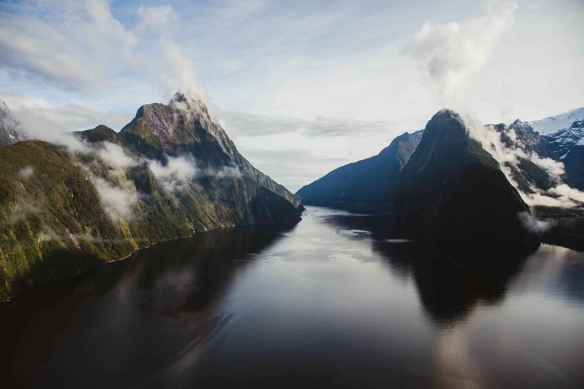 A fjord surrounded by mountains with clouds. 2