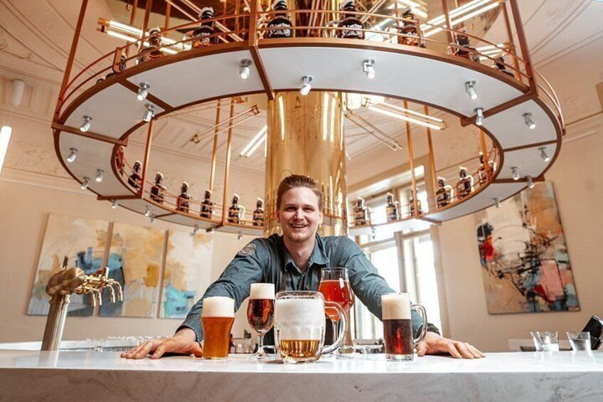 A person seated at a bar with multiple glasses of beer and a large beer mug. 4