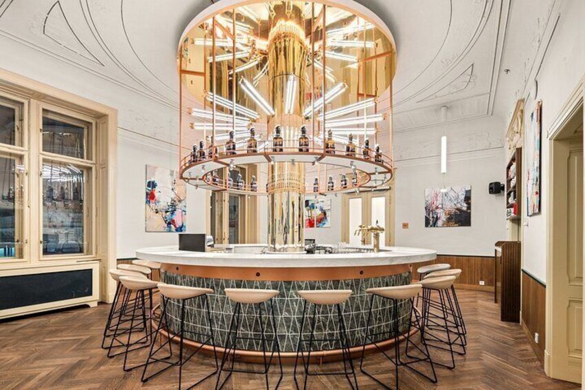 A circular bar with stools, a central chandelier, and artwork on the walls. 3