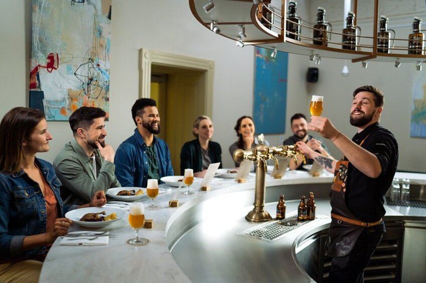 A bar setting with a bartender serving drinks to a group of people seated at a table. 1