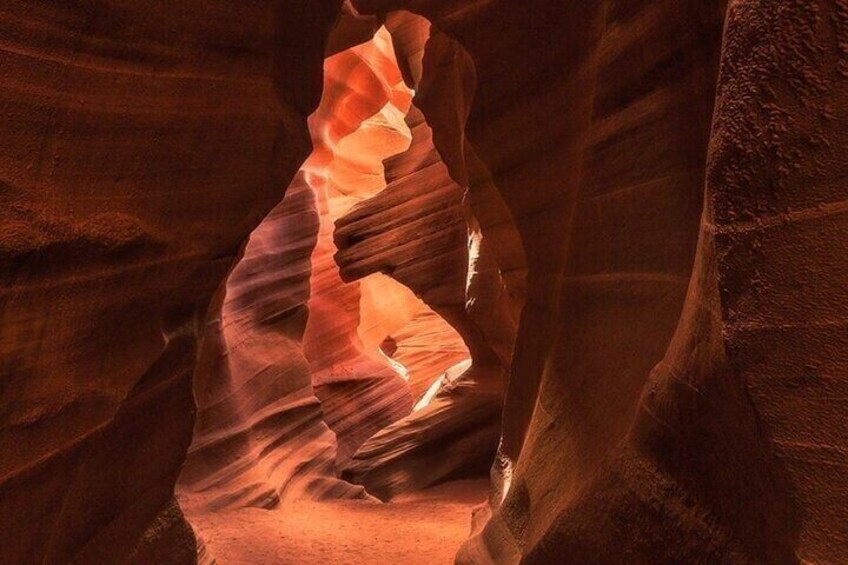 A narrow canyon with smooth, curved rock walls and a bright light source illuminating the interior. 1