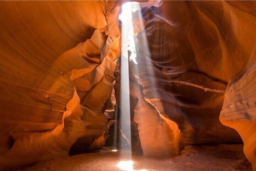 A canyon with a narrow passageway and a vertical shaft of light. 2