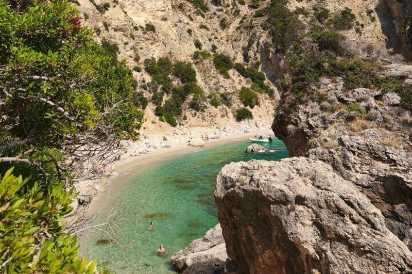 A coastal landscape with a clear beach, rocky cliffs, and a cove. 1