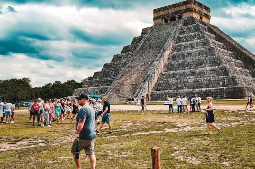 A large pyramid structure with tourists around it. 1