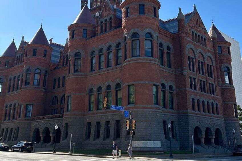 A large, historic brick building with arched windows and a turret. 5