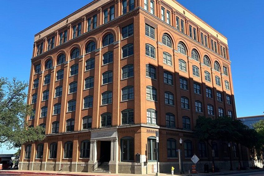 A large red brick building with multiple windows and a corner entrance. 2