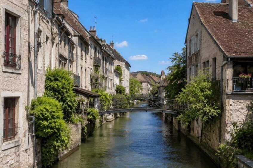 A narrow canal flanked by historic stone buildings with a bridge crossing over it. 4