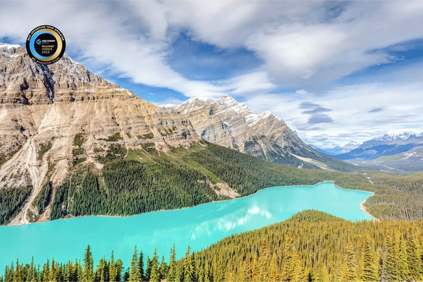 A mountain landscape with a turquoise lake and dense forest. 1