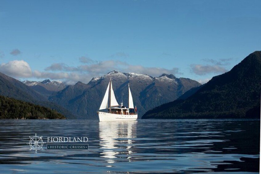A sailboat on calm waters with mountains in the background. 1