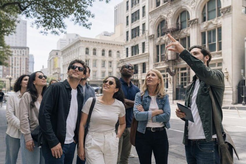 A group of people standing on a city street with historic buildings in the background. 1