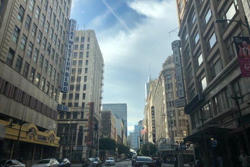 A city street lined with tall buildings, including a theater and a building with a sign that reads 'Vincent.' 4