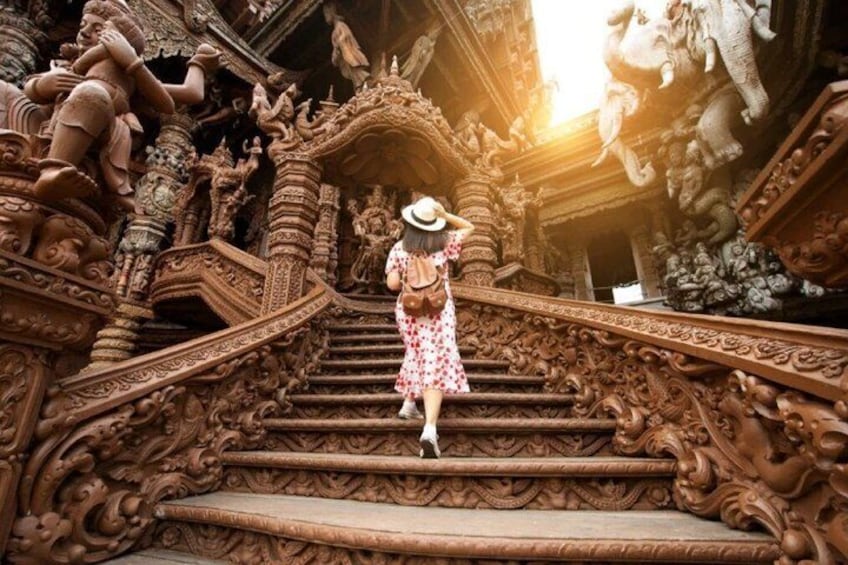A person descending a intricately carved staircase with ornate designs and statues. 1