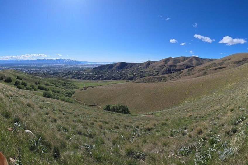 A hilly landscape with a valley, distant mountains, and a clear sky. 3