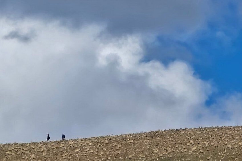 A barren hill with two people walking. 5