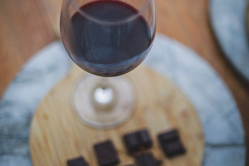 A glass of red wine with a wooden board in the background. 3