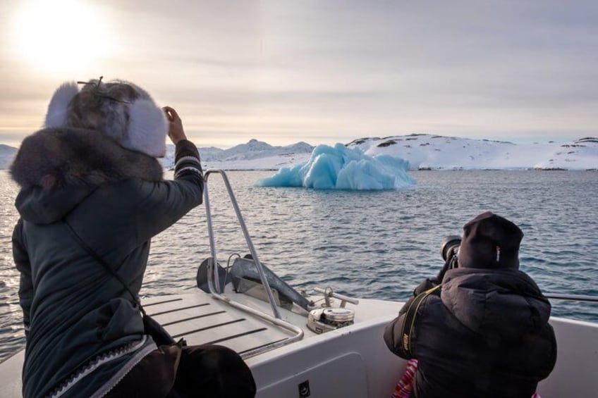 A person taking a photograph of an iceberg in a polar region. 4