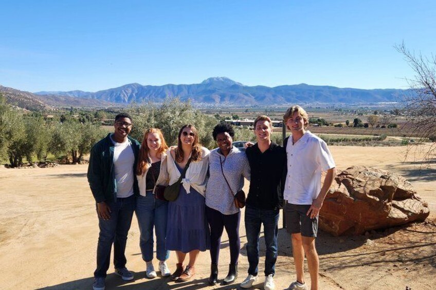 A group of people standing outdoors with a desert landscape and mountains in the background. 2